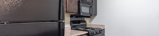 a kitchen with a black refrigerator freezer and a stove top oven