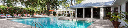 A pool surrounded by trees and a building.