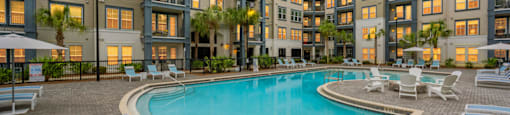 a swimming pool in front of an apartment building at sunset