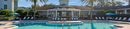 a swimming pool with chairs and a building in the background