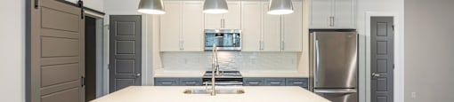 a white kitchen with a large island and stainless steel appliances