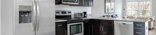 A modern kitchen with a stainless steel refrigerator and black cabinets.
