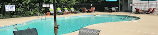 a swimming pool with a table and chairs under an umbrella