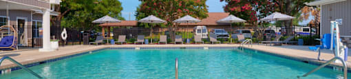 A pool with two lounge chairs in the foreground.