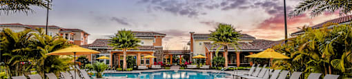 a swimming pool with lounge chairs around it at sunset