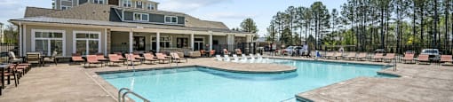 a resort style pool with lounge chairs and a building in the background