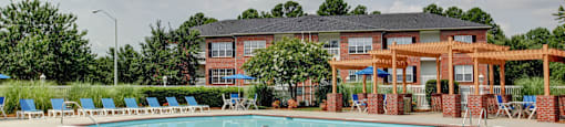 A pool with chairs and a building in the background.