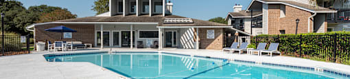 A large swimming pool with a diving board and lounge chairs.