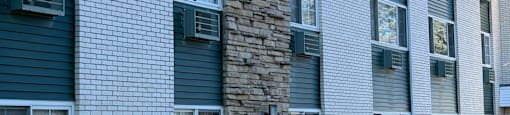 A building with a mix of grey and white bricks and a stone pillar.