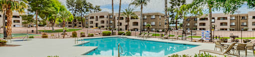 a swimming pool with palm trees and buildings in the background