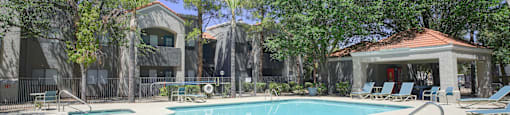 A swimming pool surrounded by trees and a building in the background.