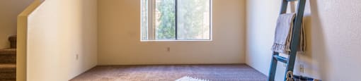 Living room with large window and rug, stairs on left