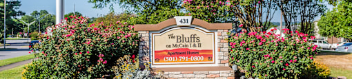 A sign for "The Bluffs" on Main Street is surrounded by greenery and flowers.
