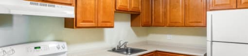 A kitchen with white appliances and wooden cabinets at Edmands House, Massachusetts, 01701