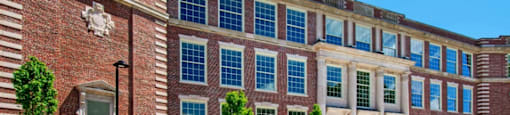 a large brick building with many windows and a street in front at Beverly Village for Living & the Arts Apartments, Beverly, 01915