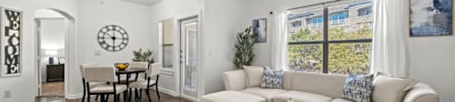 A living room with a white couch, a wooden floor, and a ceiling fan.