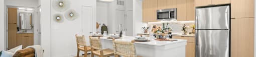 A modern kitchen with a white island and wooden chairs.