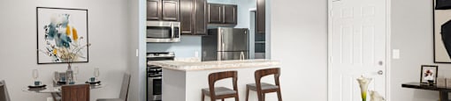 a living room with a kitchen and a bar with stools