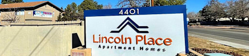 A sign for Lincoln Place Apartment Homes is displayed in front of a building.