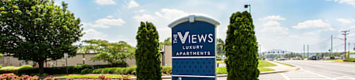 a blue sign with white writing and a blue bench in front of a parking lot