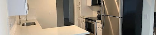 A modern kitchen with white cabinets and a black refrigerator.