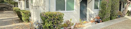 a small gray house with green shutters and a driveway