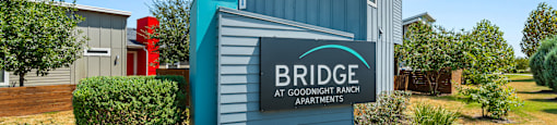 A sign for Bridge at Goodnight Ranch Apartments is in front of a building.