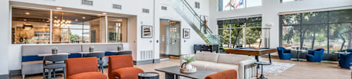 a living room with couches and chairs and a lobby with a staircase