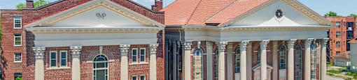 an aerial view of a brick building with columns and a bell tower