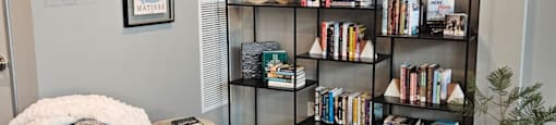 A room with a bookshelf, a chair, and a small tree.