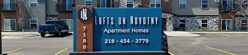 a sign in a parking lot in front of an apartment building