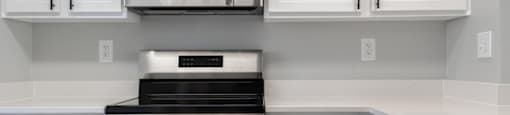 A modern kitchen with white cabinets and black appliances.