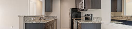 A kitchen with dark wood cabinets and a granite countertop.