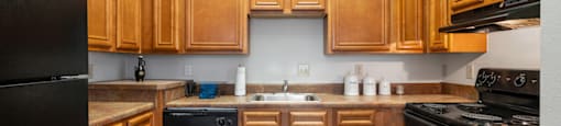 A kitchen with wooden cabinets and black appliances.