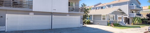 A white two-story apartment building with a garage door and balcony.