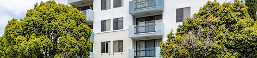a white apartment building with blue stairs and trees