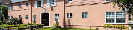 a pink building with a green lawn and a metal fence in front of it