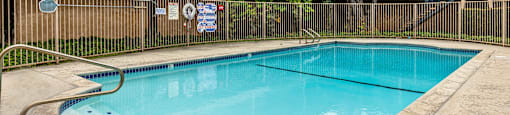 a swimming pool with a fence around it and a building in the background