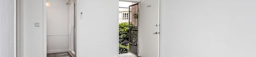 A room with white walls and wooden flooring with two doors.