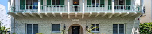 a mansion with a white brick facade and green shutters
