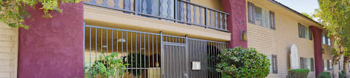 a yellow building with a red and yellow wall and a black gate in front of it