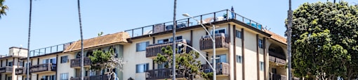 an apartment building on a street with palm trees