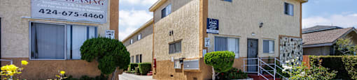A street view of a Now Leasing sign in front of a building.
