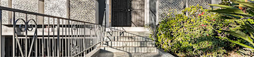A building with a black door and a metal railing.