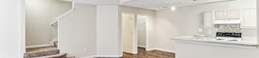 a renovated living room with a kitchen and a ceiling fan