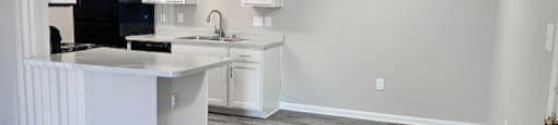 A kitchen with a black fridge and white cabinets.