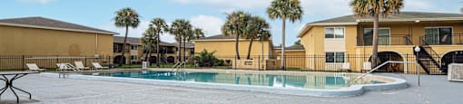 our resort style swimming pool is next to our buildings and palm trees