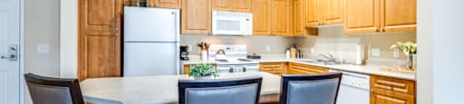 a kitchen with wooden cabinets and a counter top with three chairs