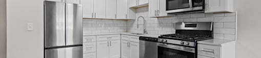 A kitchen with stainless steel appliances and white cabinets.