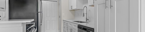 A kitchen with white cabinets and a black refrigerator.